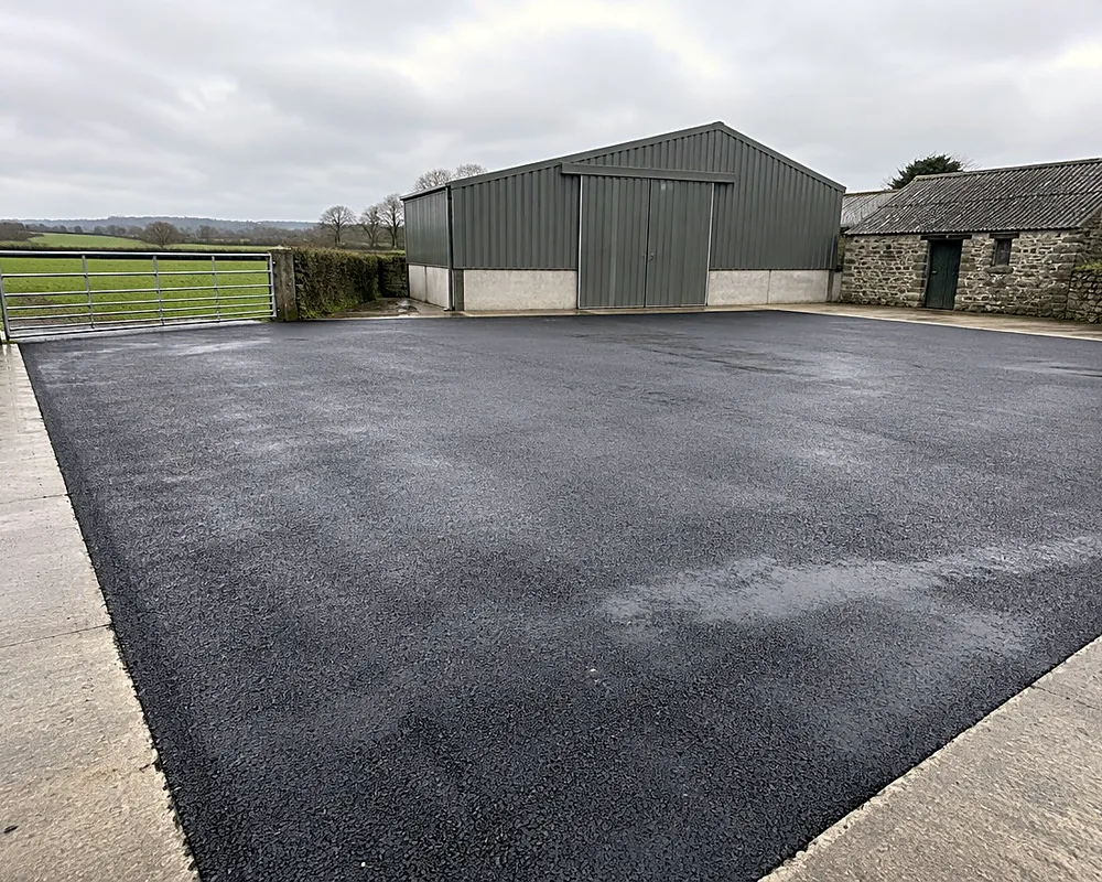 A tarmacadam farm yard in front of farm sheds