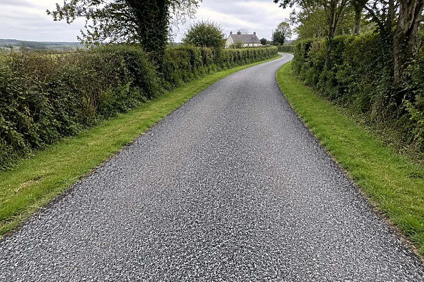 A tar and chip private lane between hedgerows